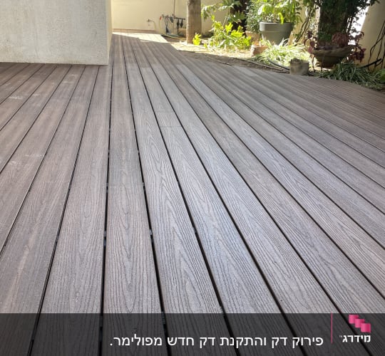 דק עץ חום בגינה עם צמחייה מסביב